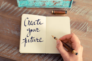 Retro effect and toned image of a woman hand writing a note with a fountain pen on a notebook. Motivational concept with handwritten text CREATE YOUR FUTURE